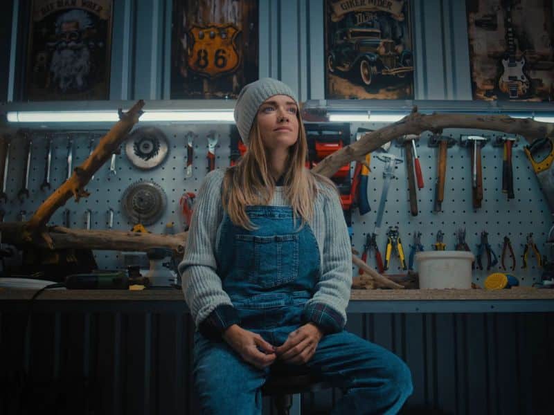 devojka sedi u radionici na ormariću za alat